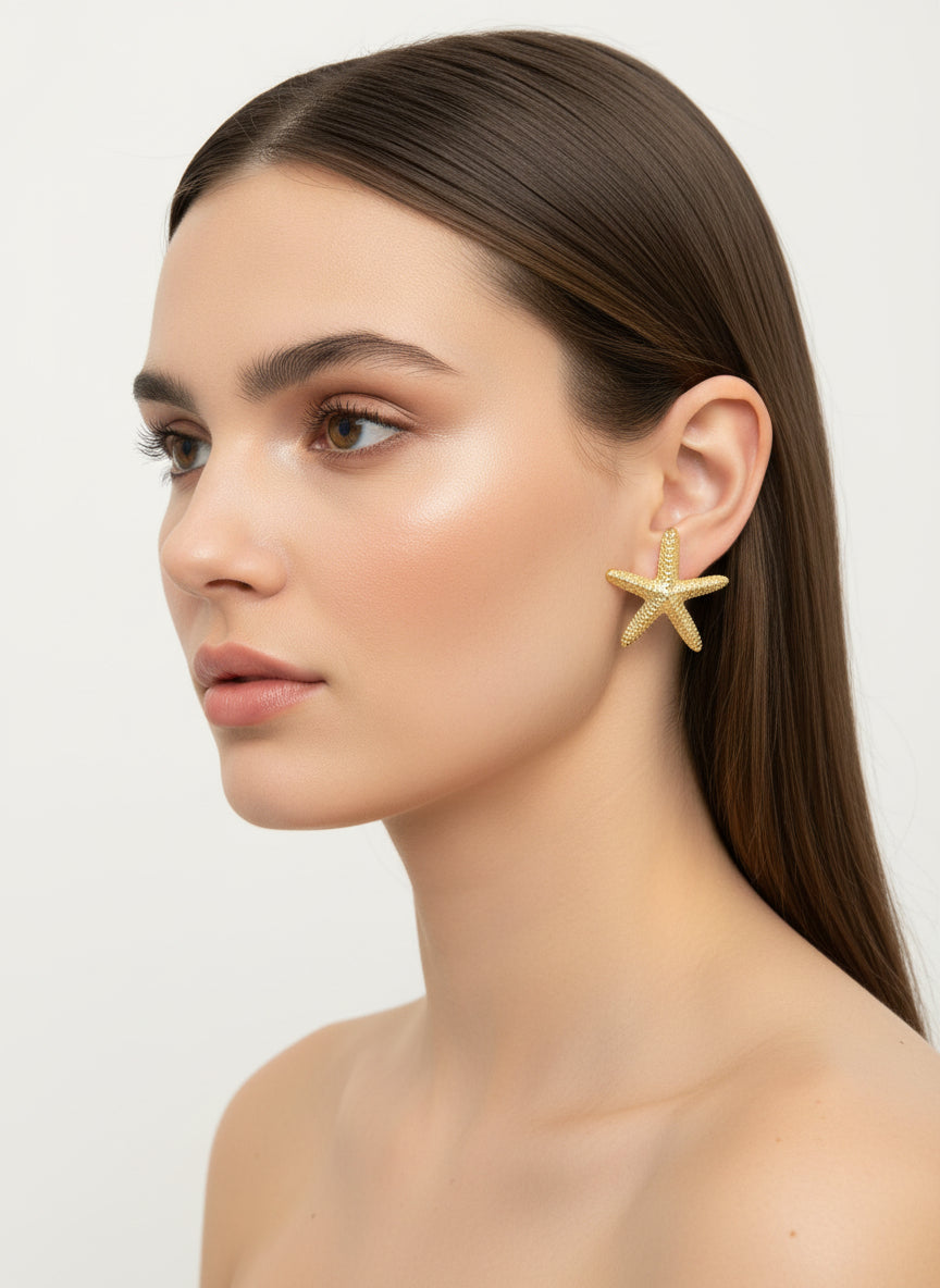 Woman wearing starfish-shaped earrings against a plain background
