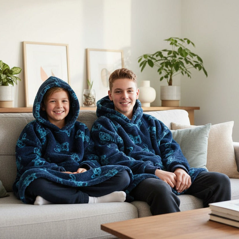 Two kids on a sofa in matching navy Stitch hooded blankets