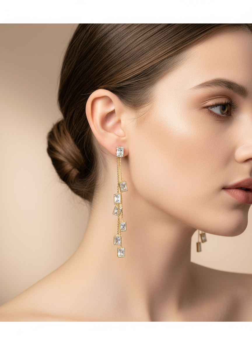 Close-up of a woman wearing gold teardrop earrings with clear stones on a beige background