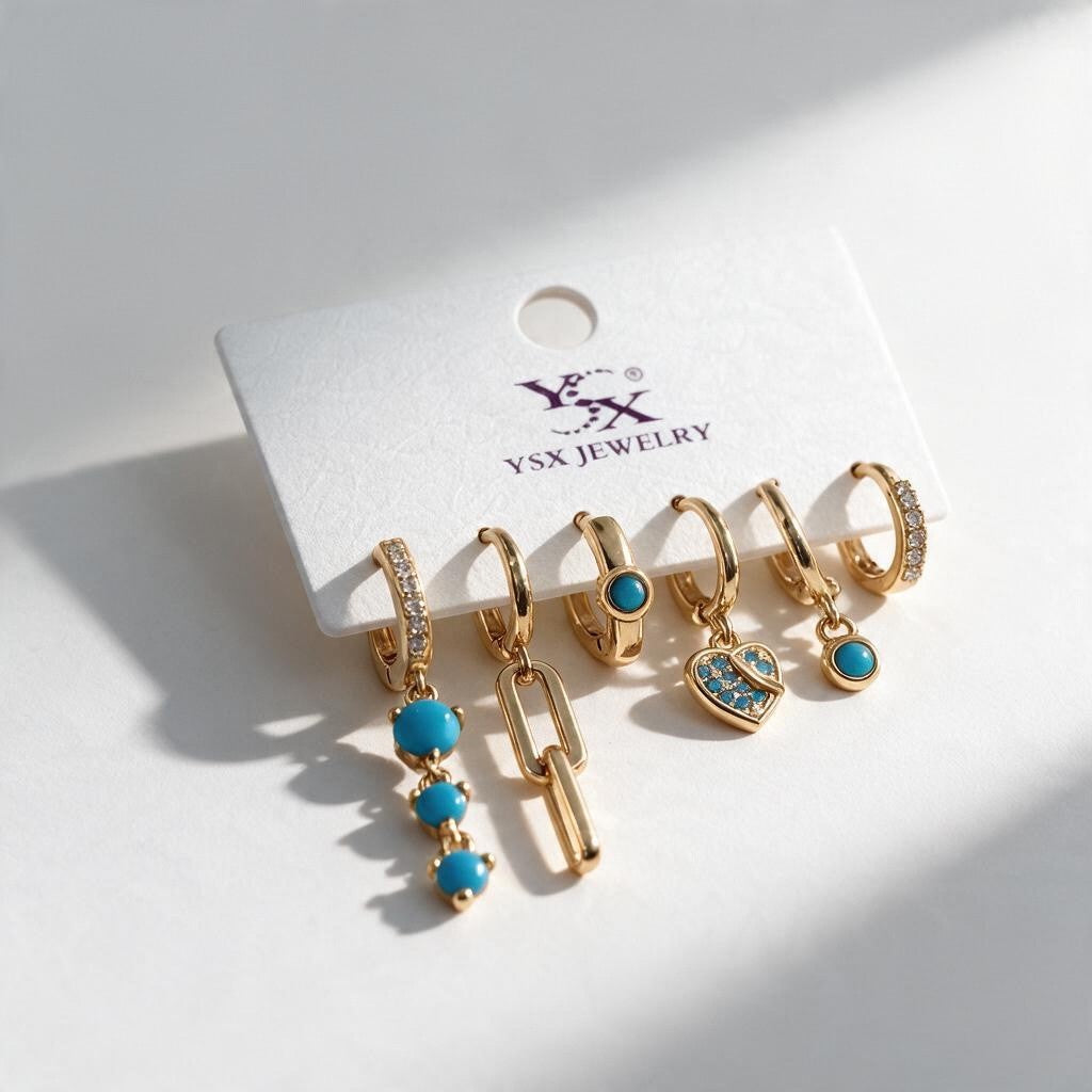 Six single gold tone huggies with turquoise bead, heart and paperclip link drops on a white card