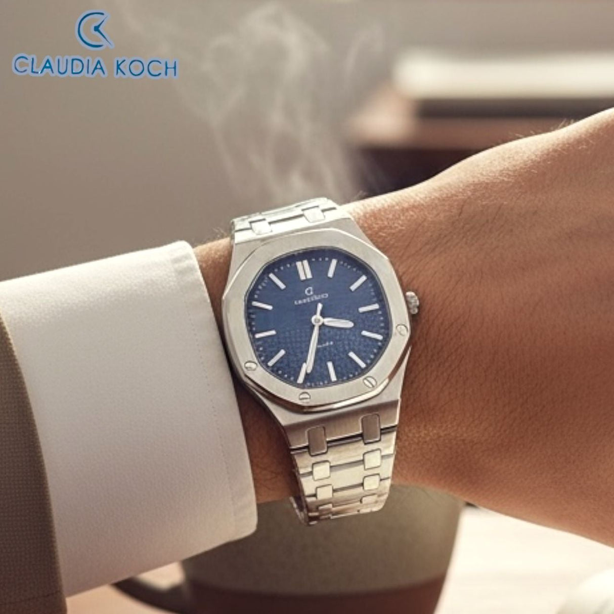 Silver urban edge watch with blue dial on a wrist, brand 'Claudia Koch' visible