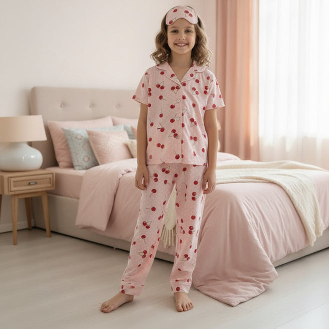 Child wearing pink pajamas with cherry pattern in a bedroom.