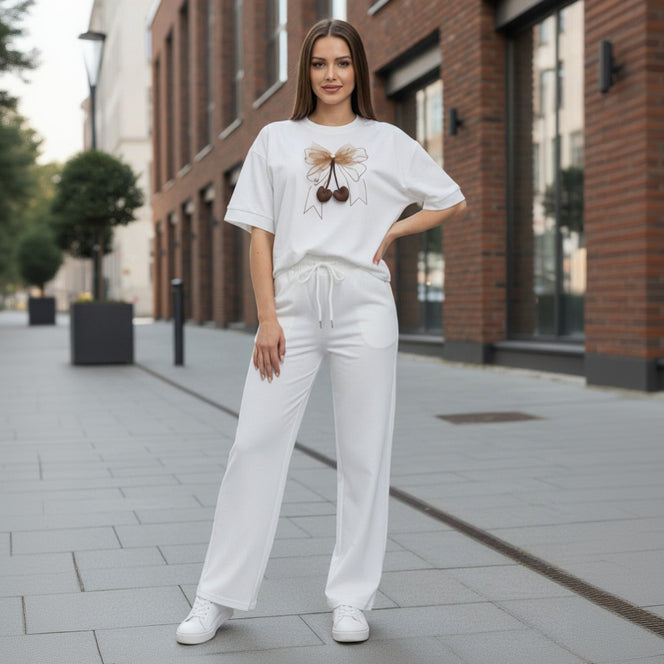 Woman wearing a white t-shirt with a graphic design and white pants on a city street.