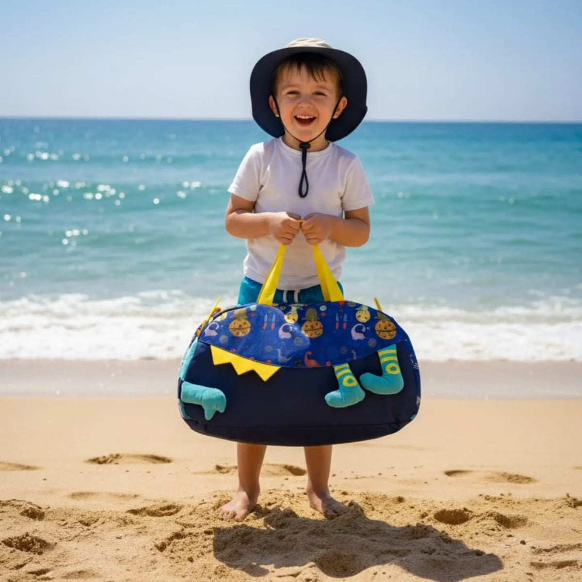 Child holding a beach bag with 'Beach Day Carry' text on a sandy beach.