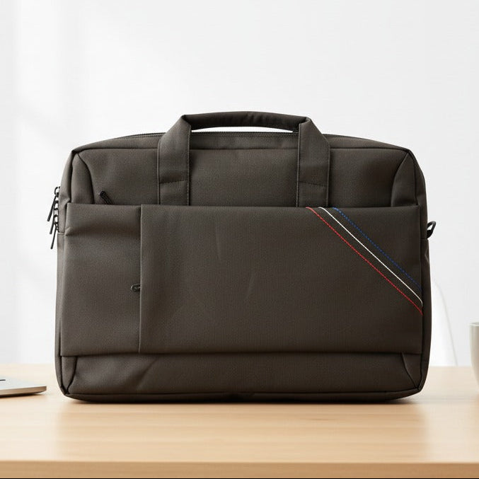 Black laptop bag on a wooden desk with a laptop, mug, and notebook in the background.