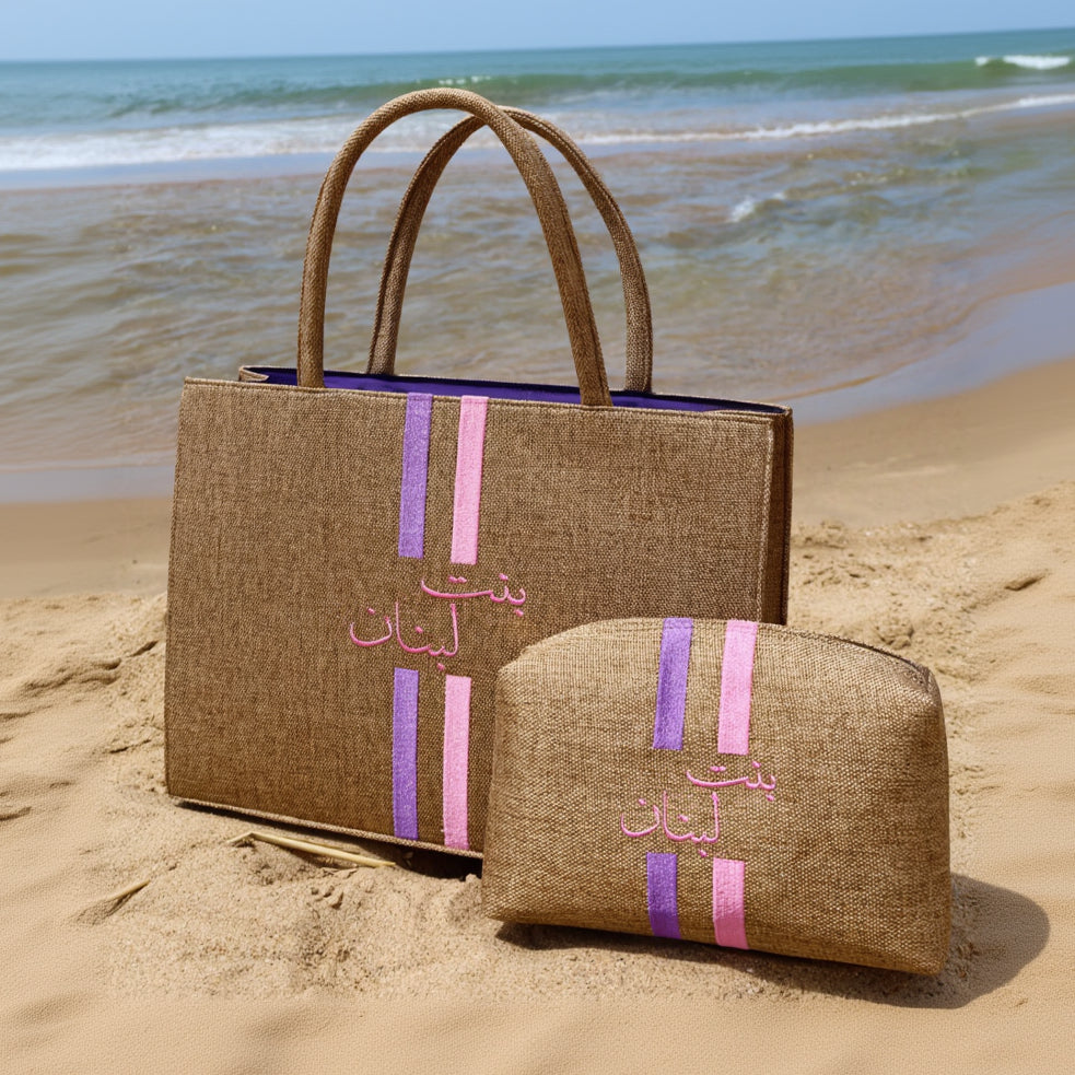 Two brown bags with pink and purple stripes on a sandy beach.