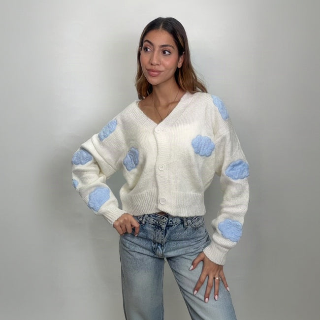 Ivory V neck button cardigan with puffy blue clouds, hands on hips