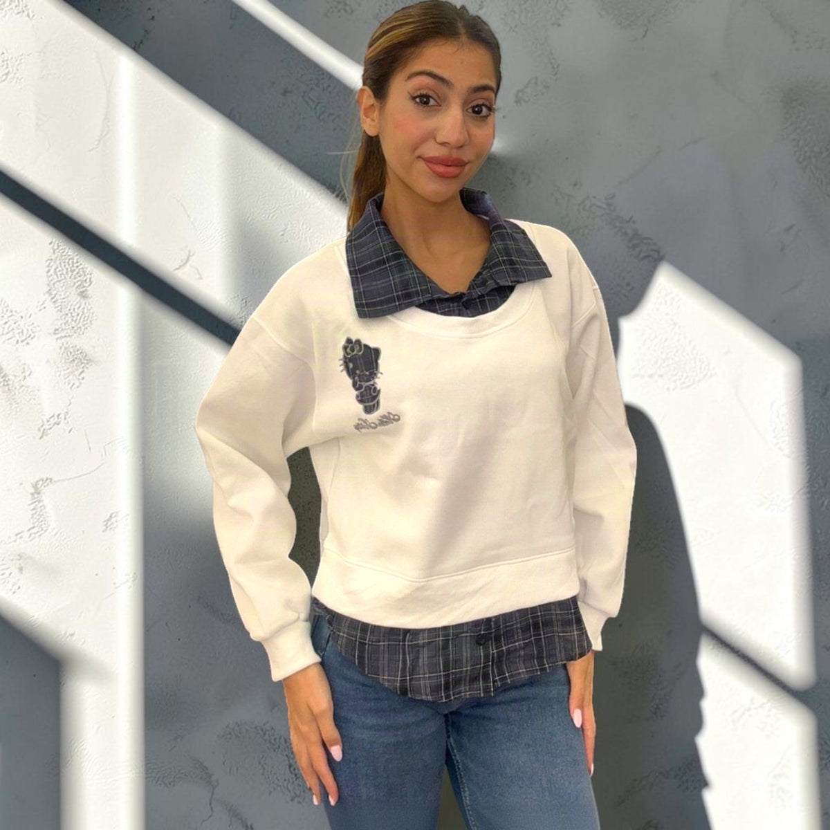 White sweatshirt with a navy check collar and check shirt hem over blue jeans