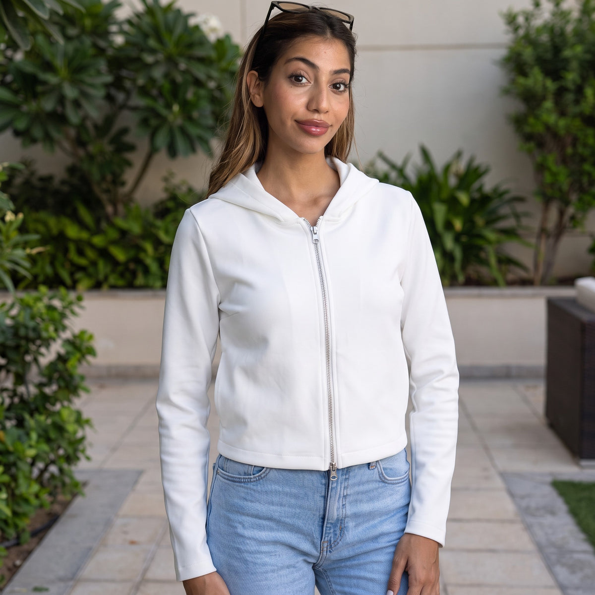 Crisp white hooded zip jacket in smooth scuba style fabric, shown front on in a garden