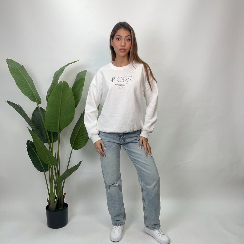 Full length view of a white Fiore script sweatshirt styled with straight leg jeans and sneakers