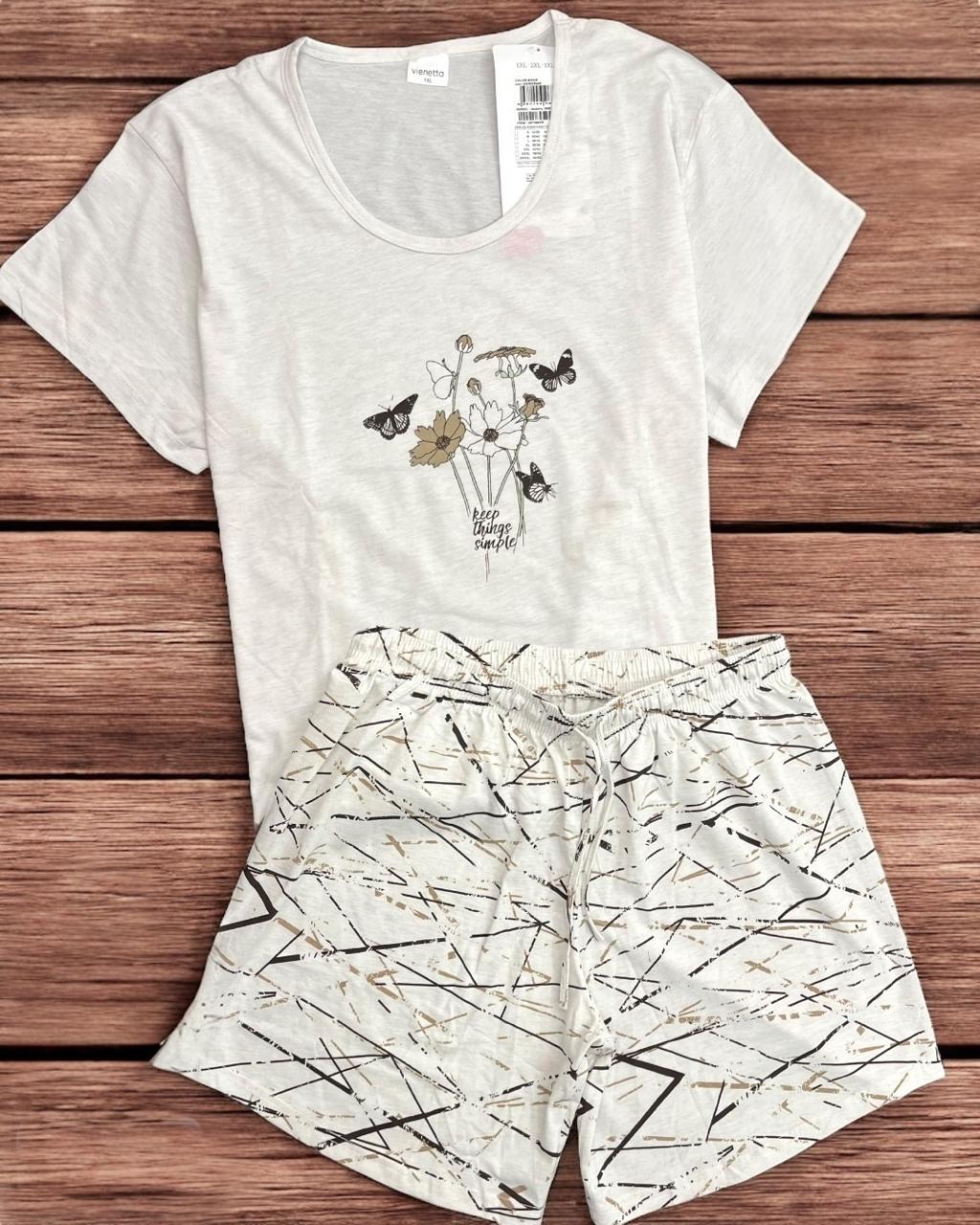 White t-shirt and shorts pyjama set with nature-themed design on a wooden surface