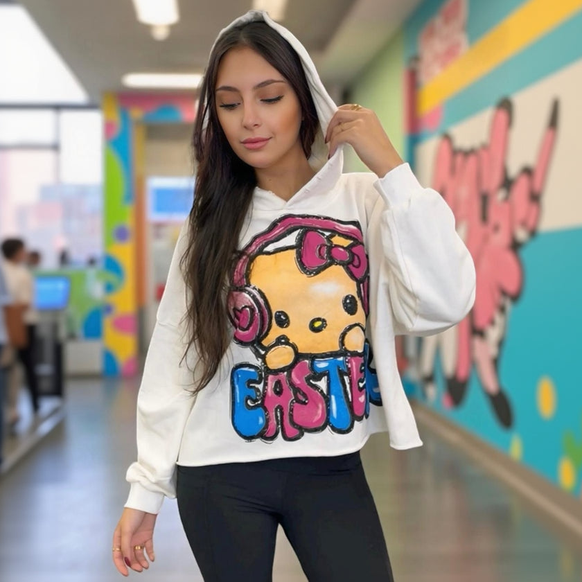 Person wearing a white hoodie with a colorful graphic design of Hello Kitty in a school hallway