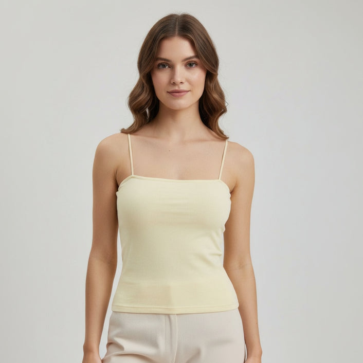Woman wearing a light yellow spaghetti strap top against a plain background