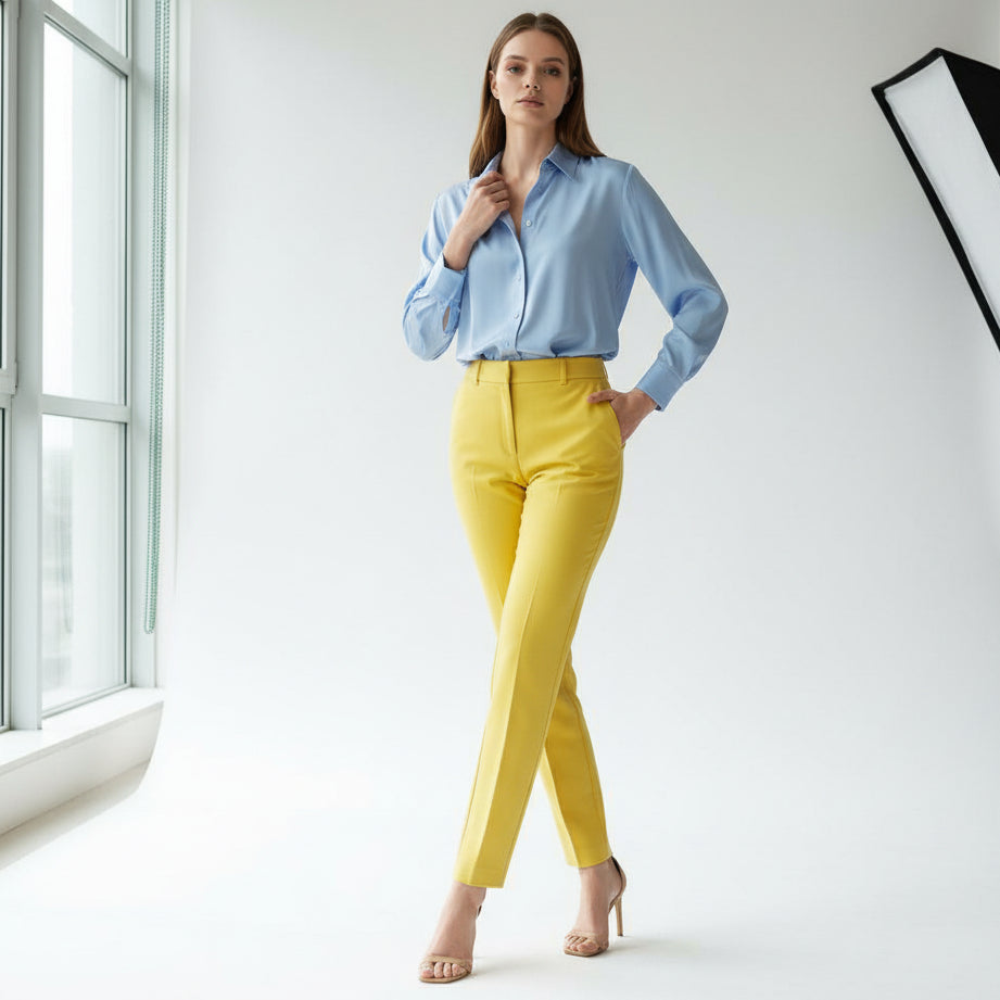 Woman wearing a white top and yellow pants in a minimalistic room
