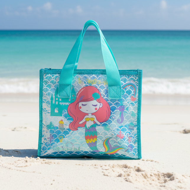 Mermaid-themed tote bag on a sandy beach with a mountain in the background