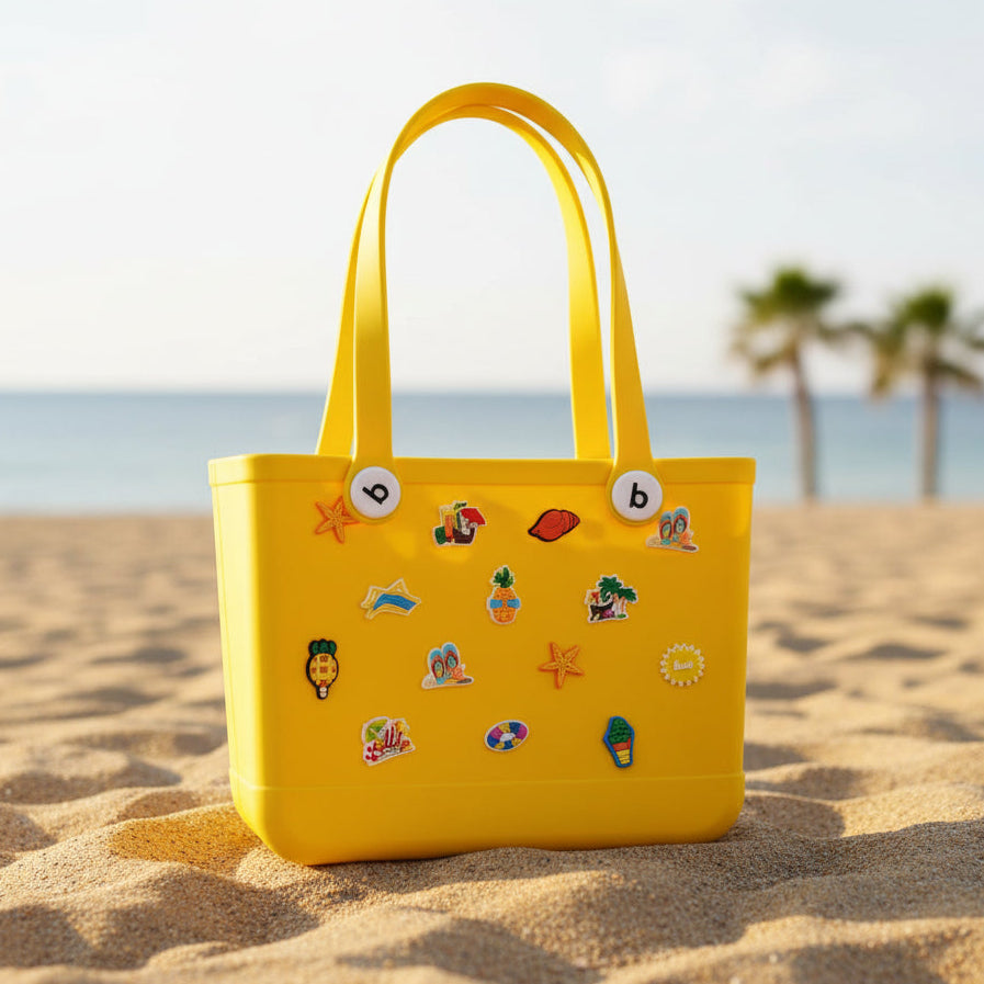 Yellow children's crocs bag with various pins on teh beach.