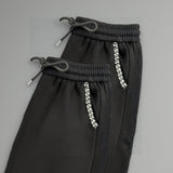 Black pants with decorative beads on a gray background