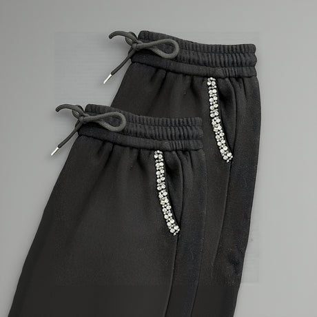 Black pants with decorative beads on a gray background