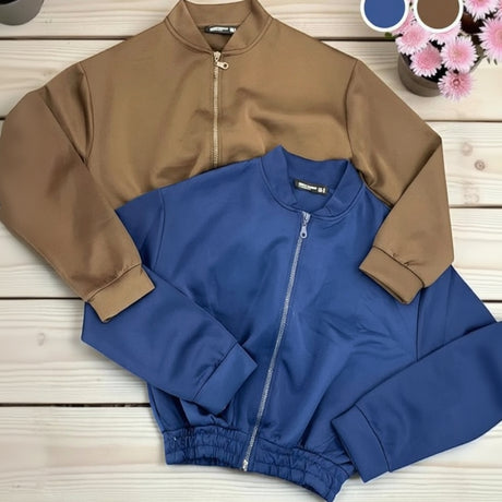 Blue and brown jacket on a wooden surface with flowers in the background
