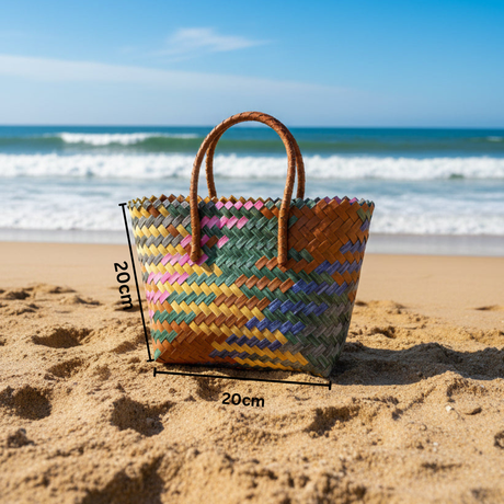 Multicolored woven bag on a sandy beach with ocean waves in the background