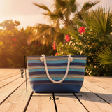 Striped beach bag on a wooden surface with palm trees and flowers in the background