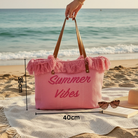 Pink tote bag with 'Summer Vibes' text on a beach setting