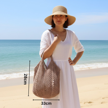 Woman holding a woven bag on a beach with ocean view