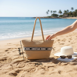 Woven bag with Christian Dior strap on a sandy beach, with a hand reaching towards it.