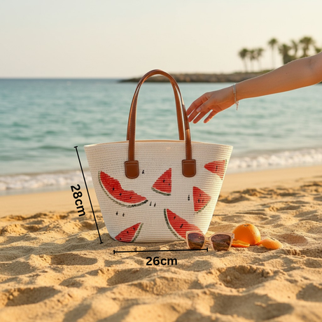 Woven bag with watermelon design on a sandy beach with ocean view