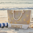 Beach bag with turtle pattern and 'BEIRUT' text on a sandy beach.