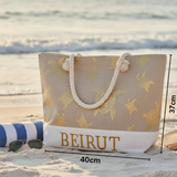 Beach bag with turtle pattern and 'BEIRUT' text on a sandy beach.