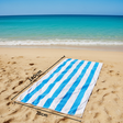 Blue and white striped towel on a sandy beach with ocean view
