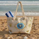 Beach bag with eye design on sand by the ocean