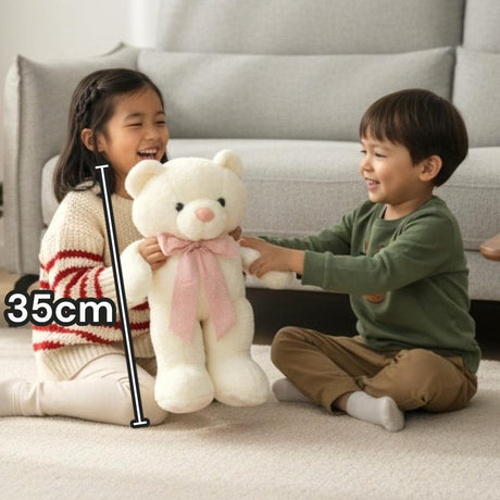 Ivory standing teddy bear with a dusty pink gingham neck bow held by two children