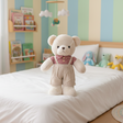 Cream teddy bear standing upright in a red gingham shirt and beige overalls