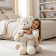 White short pile teddy bear in a red gingham scarf, hugged by a young girl