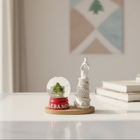 Our Lady of Lebanon tower statue beside a cedar tree globe on a red base, on a wooden tray