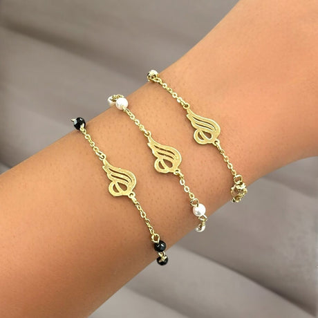 Gold Allah bracelet with and pearls on a wrist against a neutral background