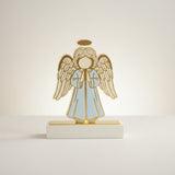 Single pale blue angel praying under a gold halo, lit warmly against cream