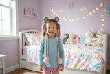 Grey fluffy ear headband with pink hanging ears and pom pom cords on a girl in a bedroom