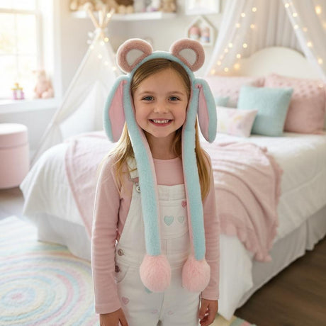 Girl wearing a mint green plush animal ear headband with pink inner ears and pom pom pull cords