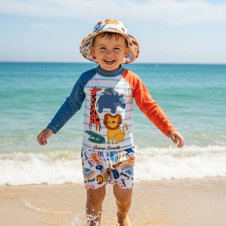 Child in a colorful swimsuit and hat with different animal prints standing on a beach with ocean in the background