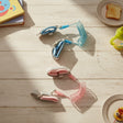 Pink and blue anti lost child wrist links laid out on a wooden floor showing padded cuffs and coil cords