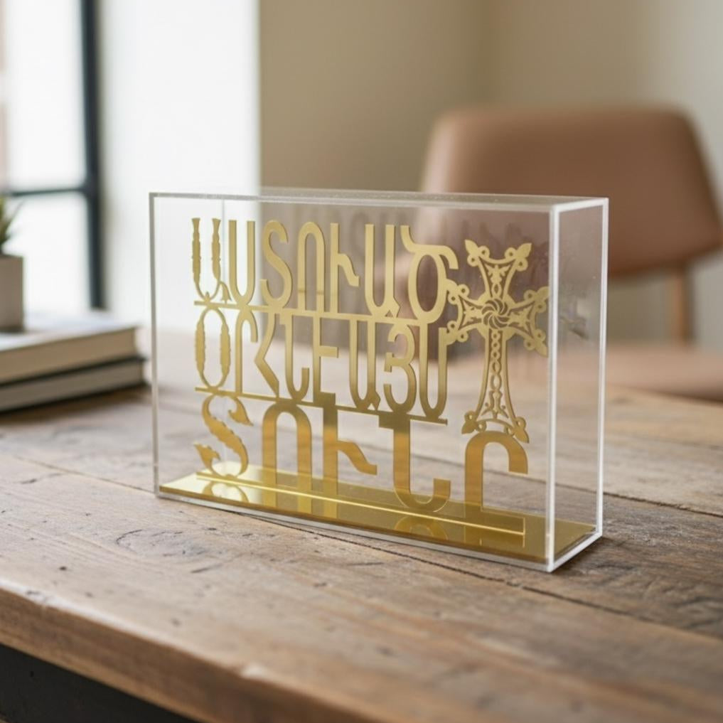 Gold cut Armenian script with an ornate khachkar cross inside a clear acrylic case