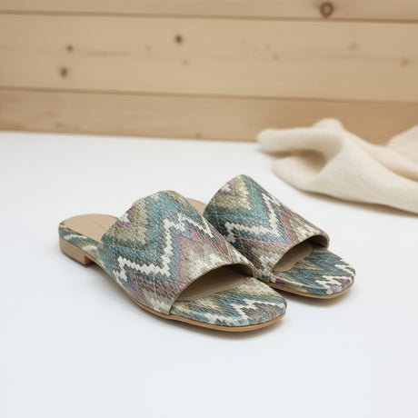 Colorful patterned slippers on a white floor and a wooden background
