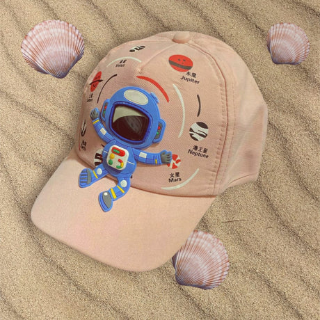 Blush pink kids cap on sand, angled to show the astronaut patch and orbiting planet prints