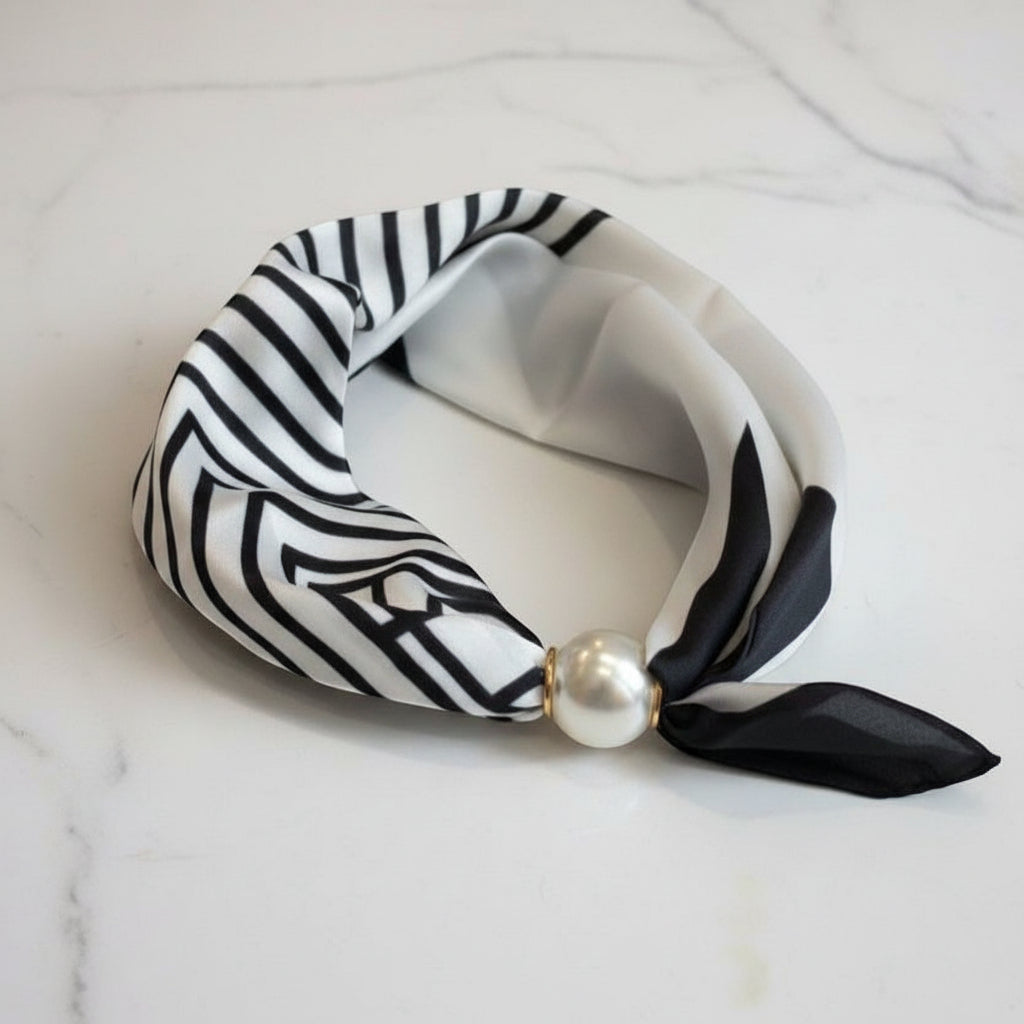 Black and white patterned foulard with a pearl accent on a marble surface