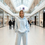 Person wearing a baby blue hoodie and sweatpants in a shopping mall