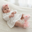 Newborn on a knit blanket in a pale pink tulle bow headband with ruffled pink tulle soft soled booties