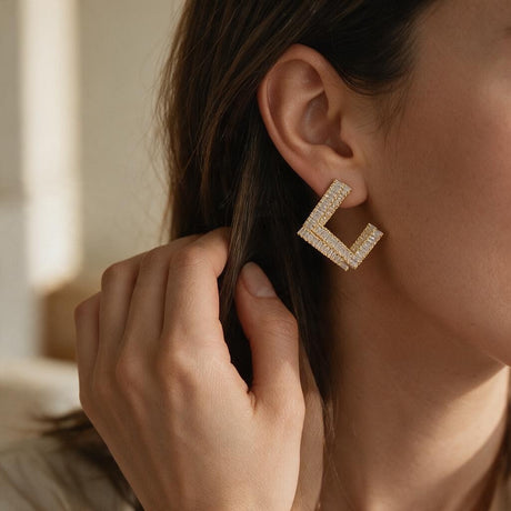 Woman tucking her hair behind her ear to show a gold open square crystal earring